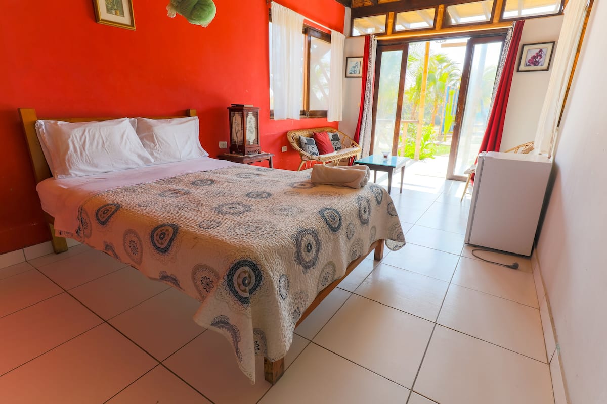 Un dormitorio con una cama, una silla, una mesa y un refrigerador.