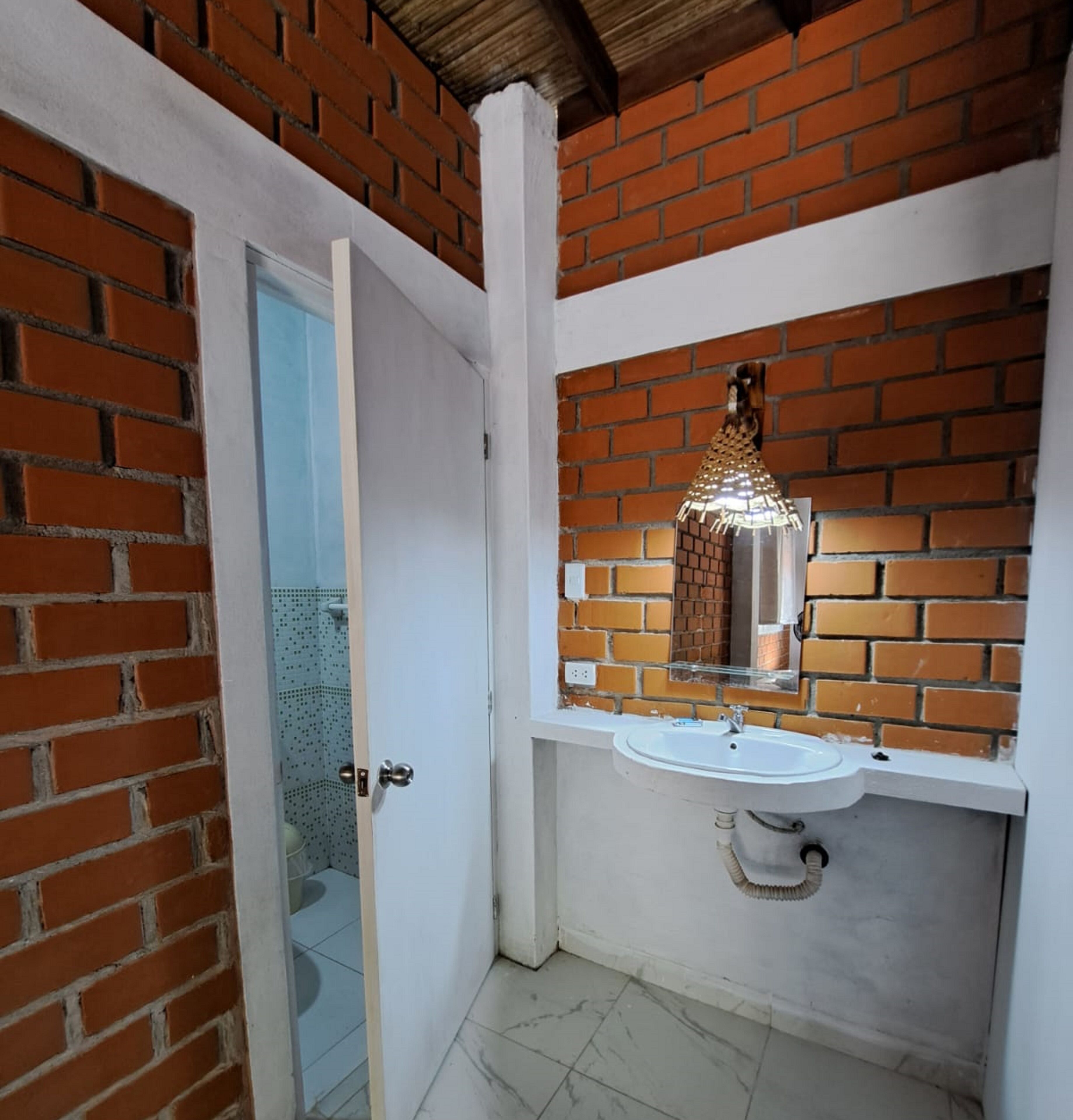 Un baño con lavamanos blanco, un espejo y un aplique decorativo sobre el lavamanos.