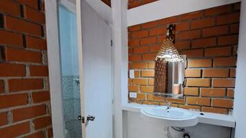 Un baño con lavamanos blanco, un espejo y un aplique decorativo sobre el lavamanos.