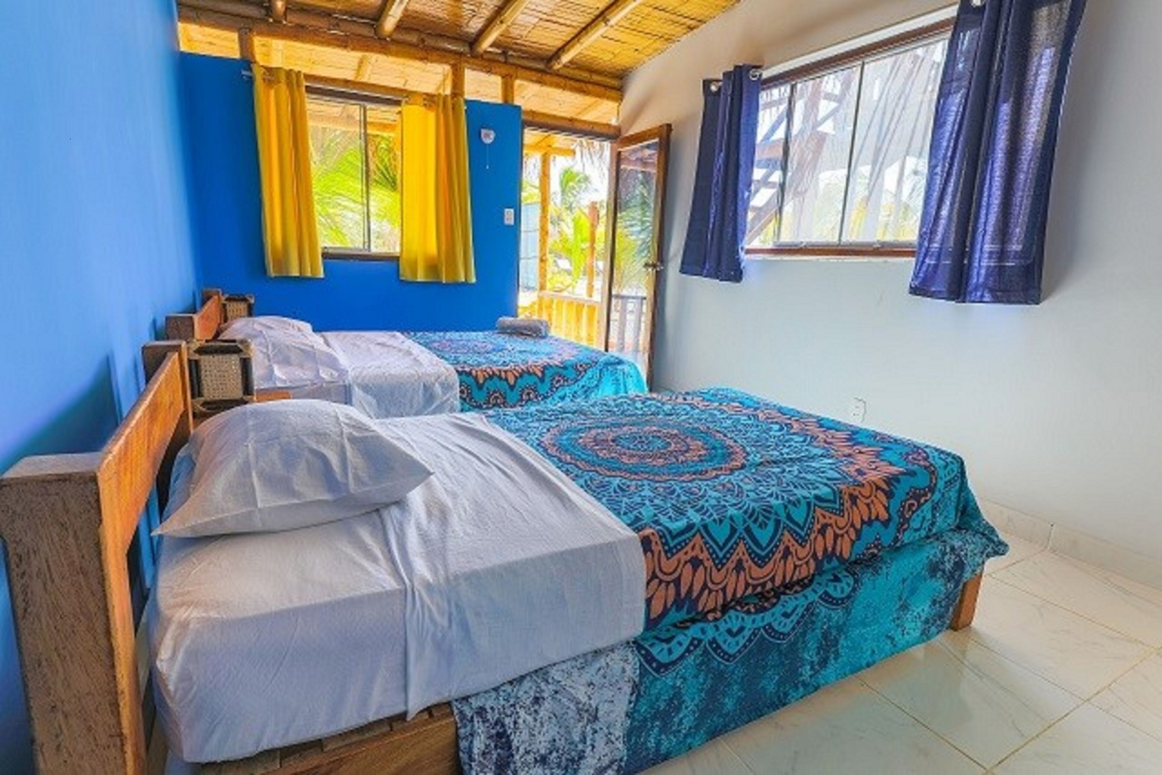Una habitación con dos camas de madera, cada una con una colcha estampada y almohadas blancas.