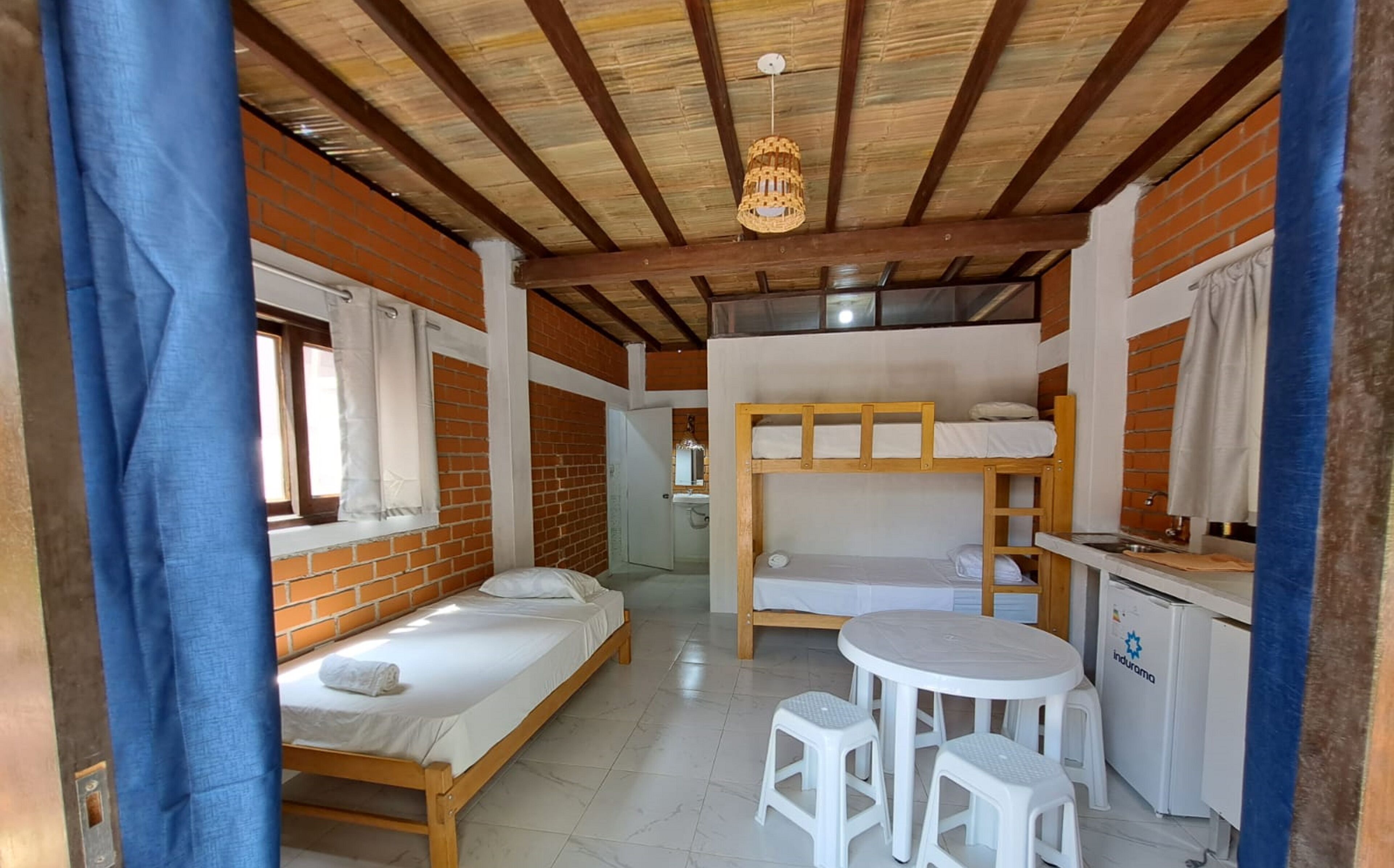 Una habitación compacta con dos literas, una kitchenette pequeña y una mesa redonda con taburetes.
