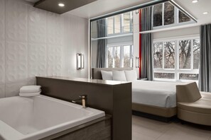 Un dormitorio moderno con un ventanal grande, una bañera y un sofá.