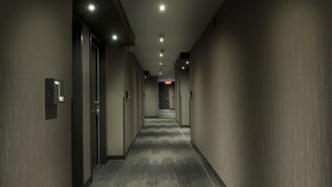 A long, narrow hallway with a carpeted floor and walls, lined with doors and illuminated by ceiling lights. - Ramada by Wyndham Laval (Laval)