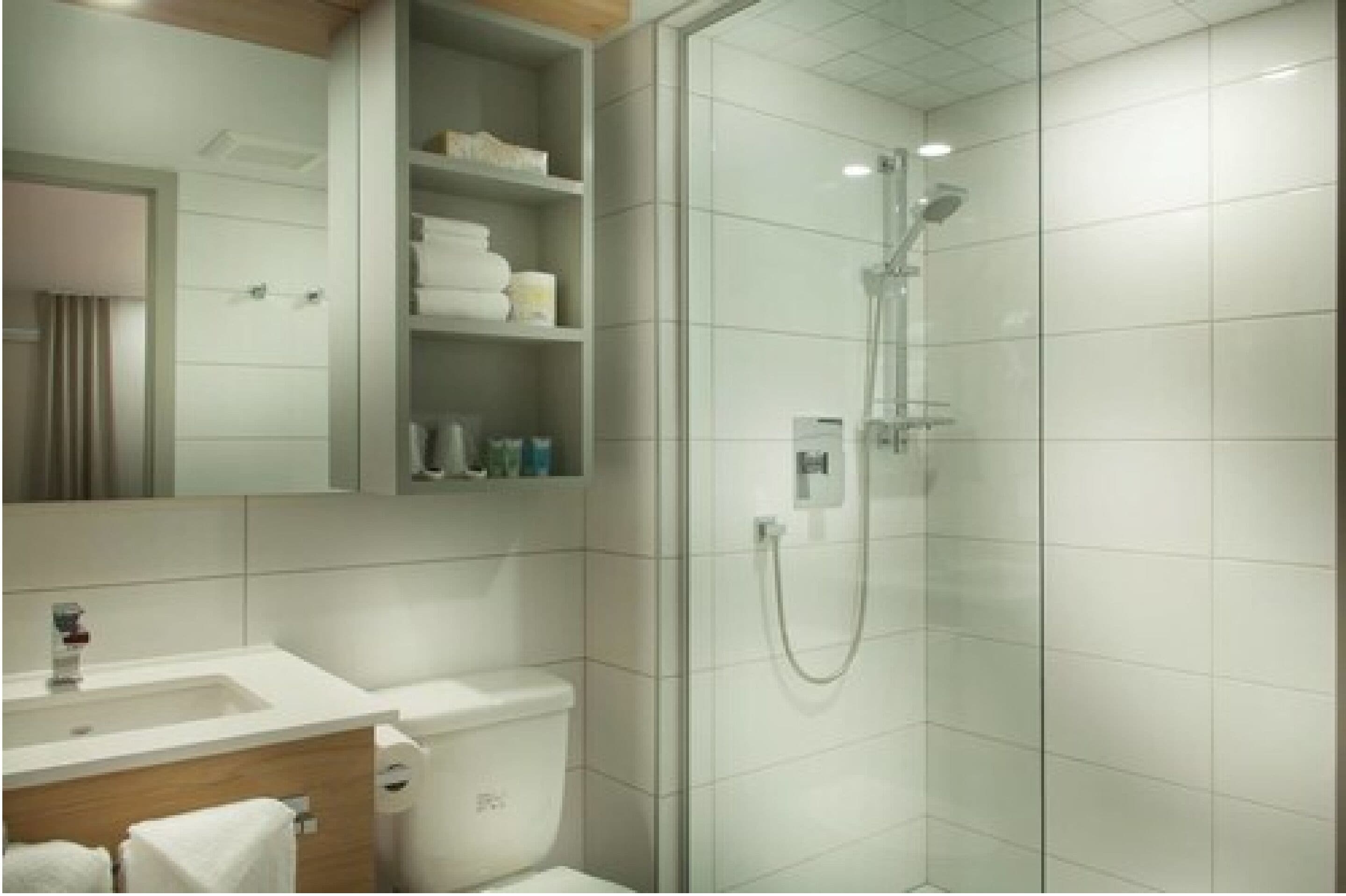 Une salle de bain moderne avec une douche à parois de verre, un lavabo blanc et un miroir au-dessus du meuble-lavabo.