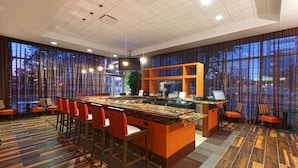 Eine moderne Bar mit einer zentralen Theke, Barhocker und einer Lounge mit Sesseln.