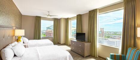 A hotel room with two beds, a television on a dresser, a chair, and a large window with a city view.