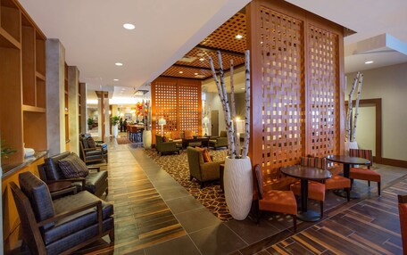 A hotel lobby with seating areas, a reception desk, and a decorative partition.