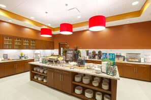 A modern kitchen with a central island, multiple counters, and a variety of appliances and food items.