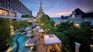 A courtyard with a swimming pool, outdoor seating, and a view of a historic cathedral. - The Strings Hotel Nagoya (Nagoya)