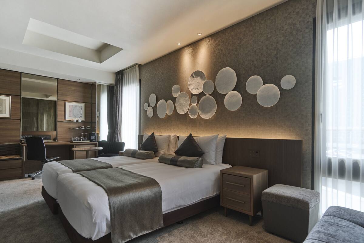Moderni hotellihuone, jossa on suuri sänky, työpöytä ja oleskelualue.
