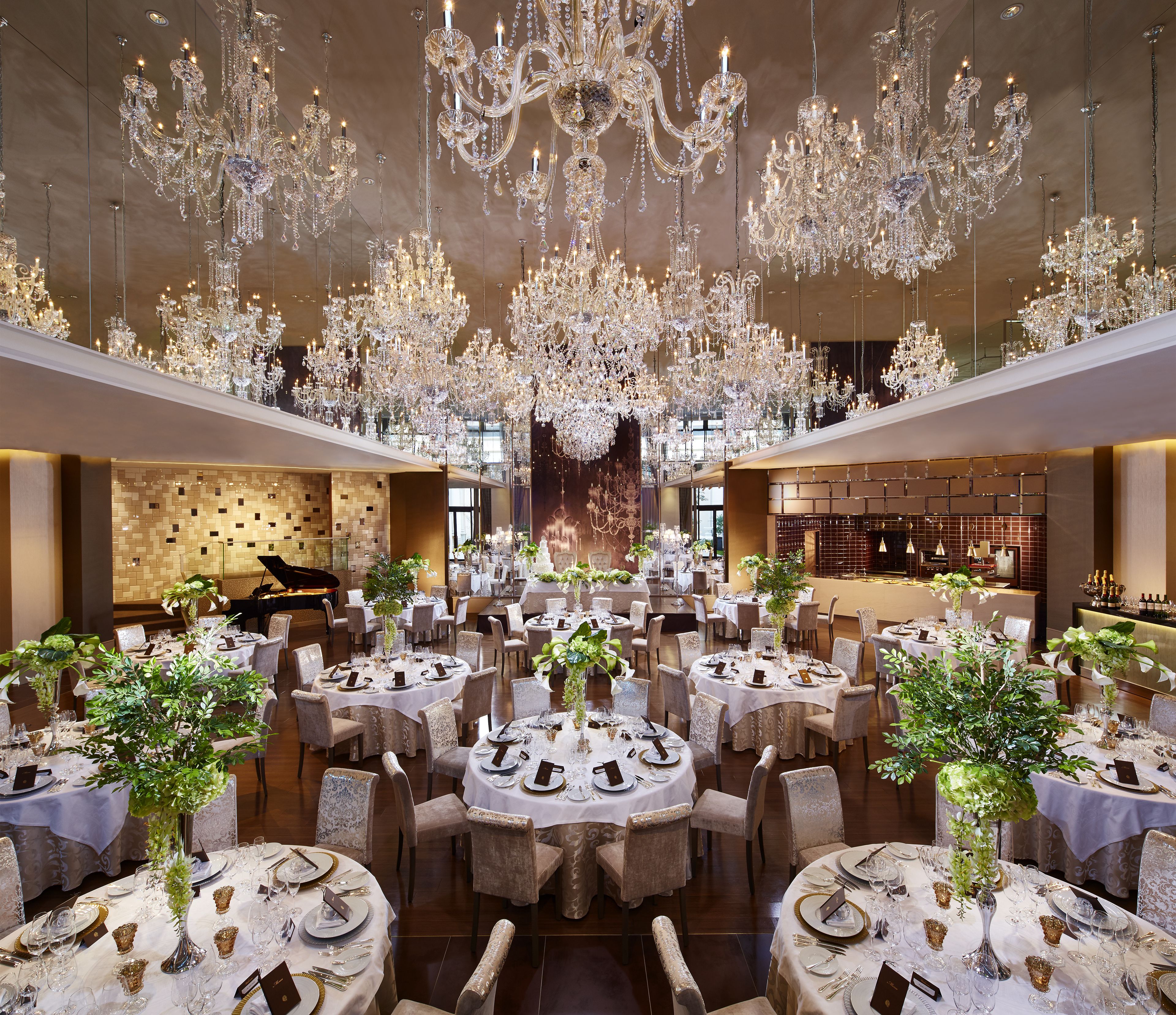 A spacious banquet hall with multiple round tables set for dining, adorned with white tablecloths and gold accents.
