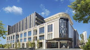 A modern hotel with a curved facade, large windows, and a prominent entrance.