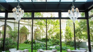A dining area with a glass wall, outdoor seating, and a chandelier. - The Strings Hotel Nagoya (Nagoya)