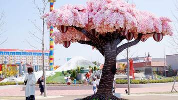 A large tree sculpture with pink blossoms in a public square.