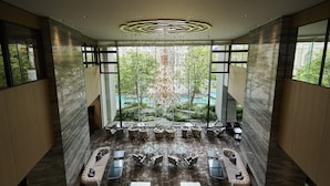 A spacious lobby with a central seating area, large windows, and a view of a garden and pool. - The Strings Hotel Nagoya (Nagoya)
