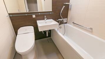 A modern bathroom with a toilet, sink, and bathtub.