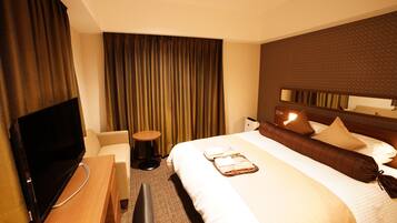 A hotel room with a bed, a TV, a desk, and a chair.