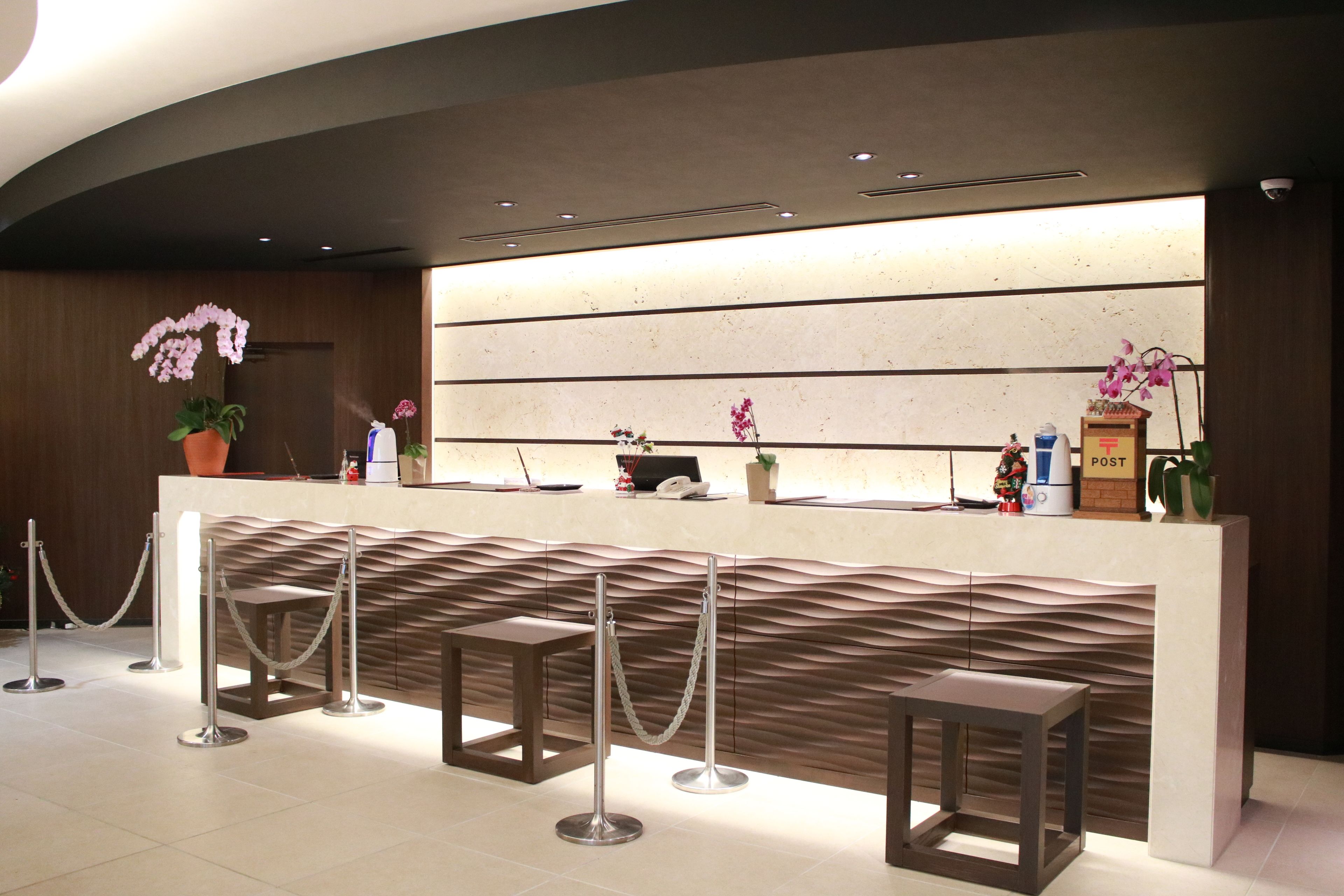 A reception area with a modern design, including a reception desk, seating area, and decorative plants.