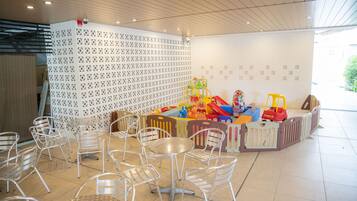 Un espace de jeux pour enfants avec des jouets colorés et un mur blanc orné de motifs.