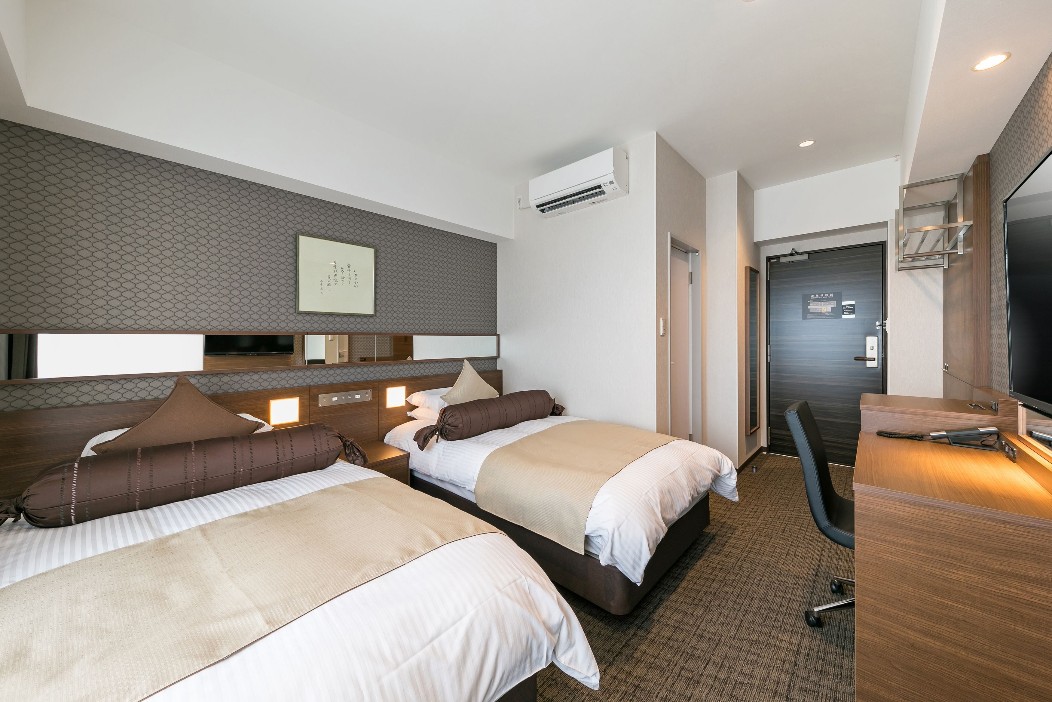 Una habitación de hotel con dos camas, un escritorio, una silla y un televisor.