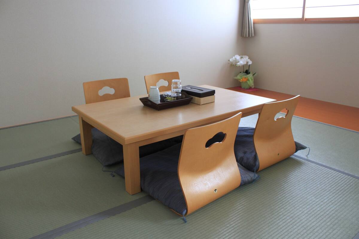 A wooden dining table with a tray of glasses and a box, surrounded by cushioned chairs.