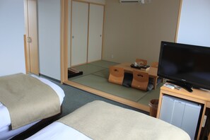 A hotel room with two beds, a television, a small table, and a futon. - Hotel Uni Goten (Rishifuji)