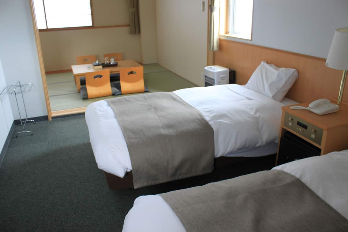 A hotel room with two beds, a desk, and a chair.