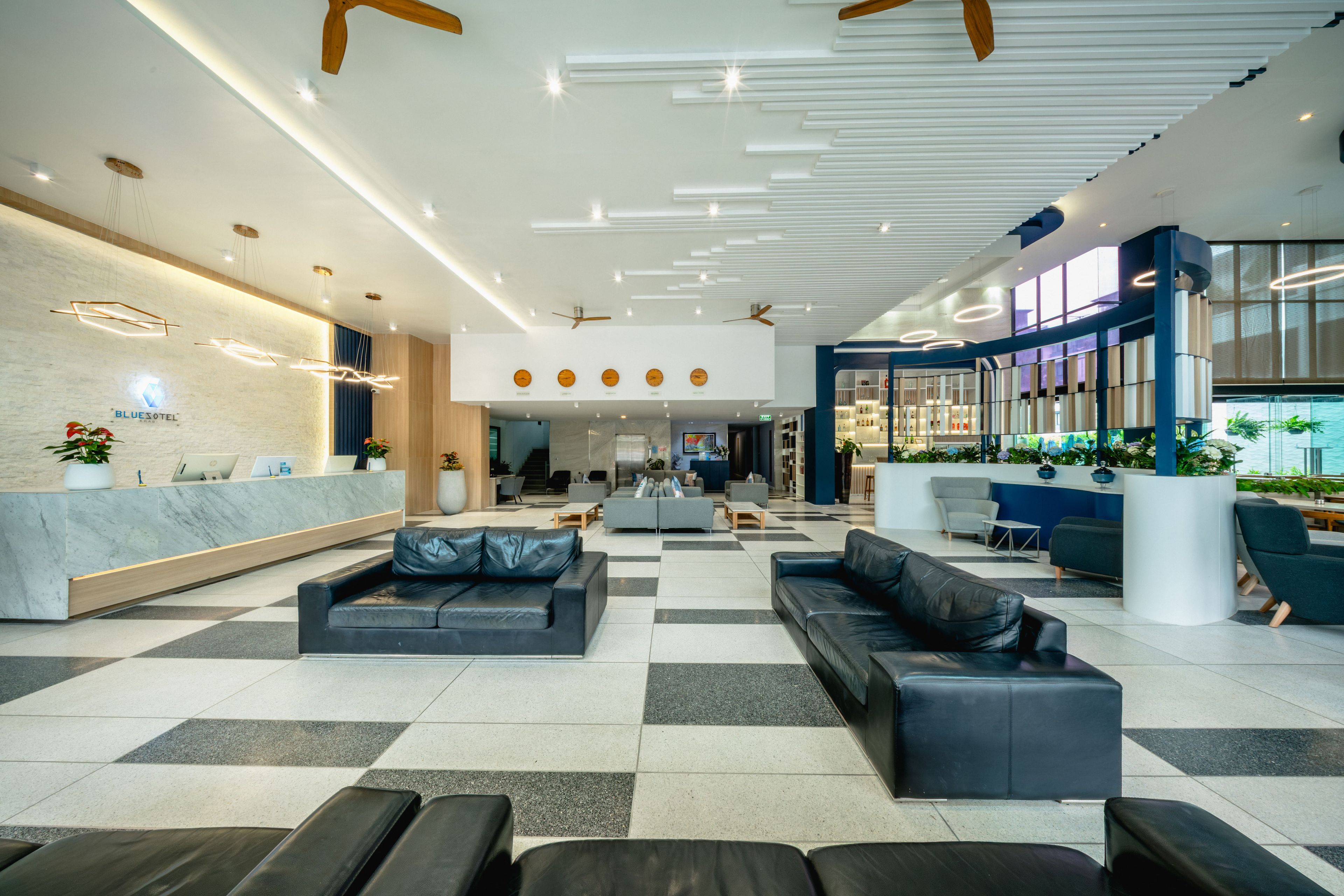 Um saguão de hotel com balcão de recepção, área de estar e bar.