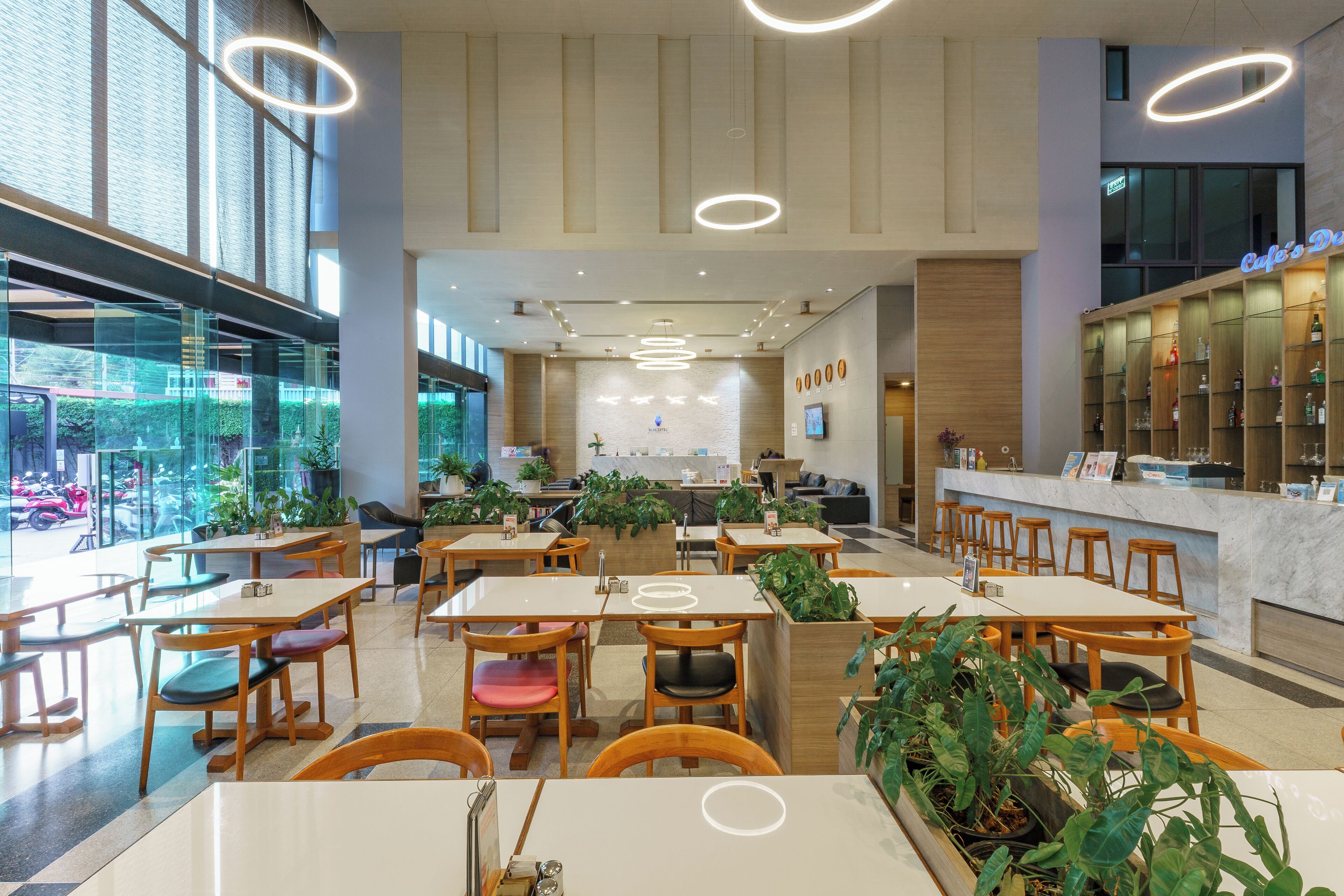 A modern cafe with multiple seating areas, including tables and chairs, and a bar counter.