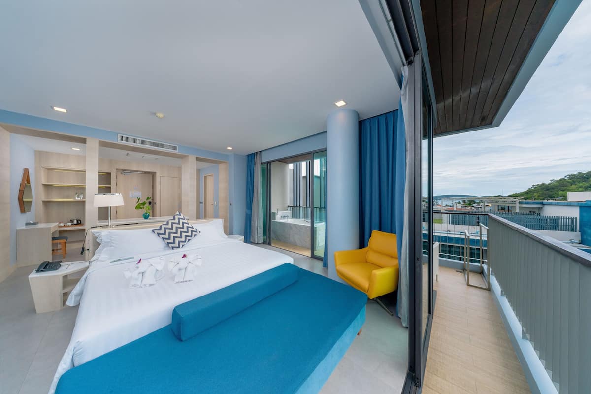 Une chambre d’hôtel moderne dotée d’un grand lit, d’un bureau et d’un balcon avec vue.
