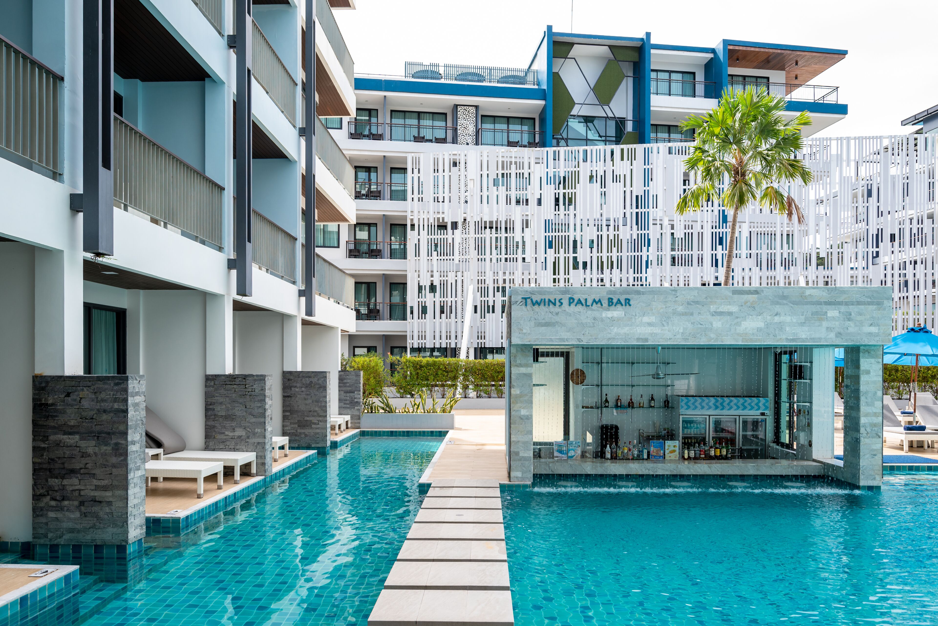 A modern hotel with a swimming pool, a bar, and a multi-story building with balconies.