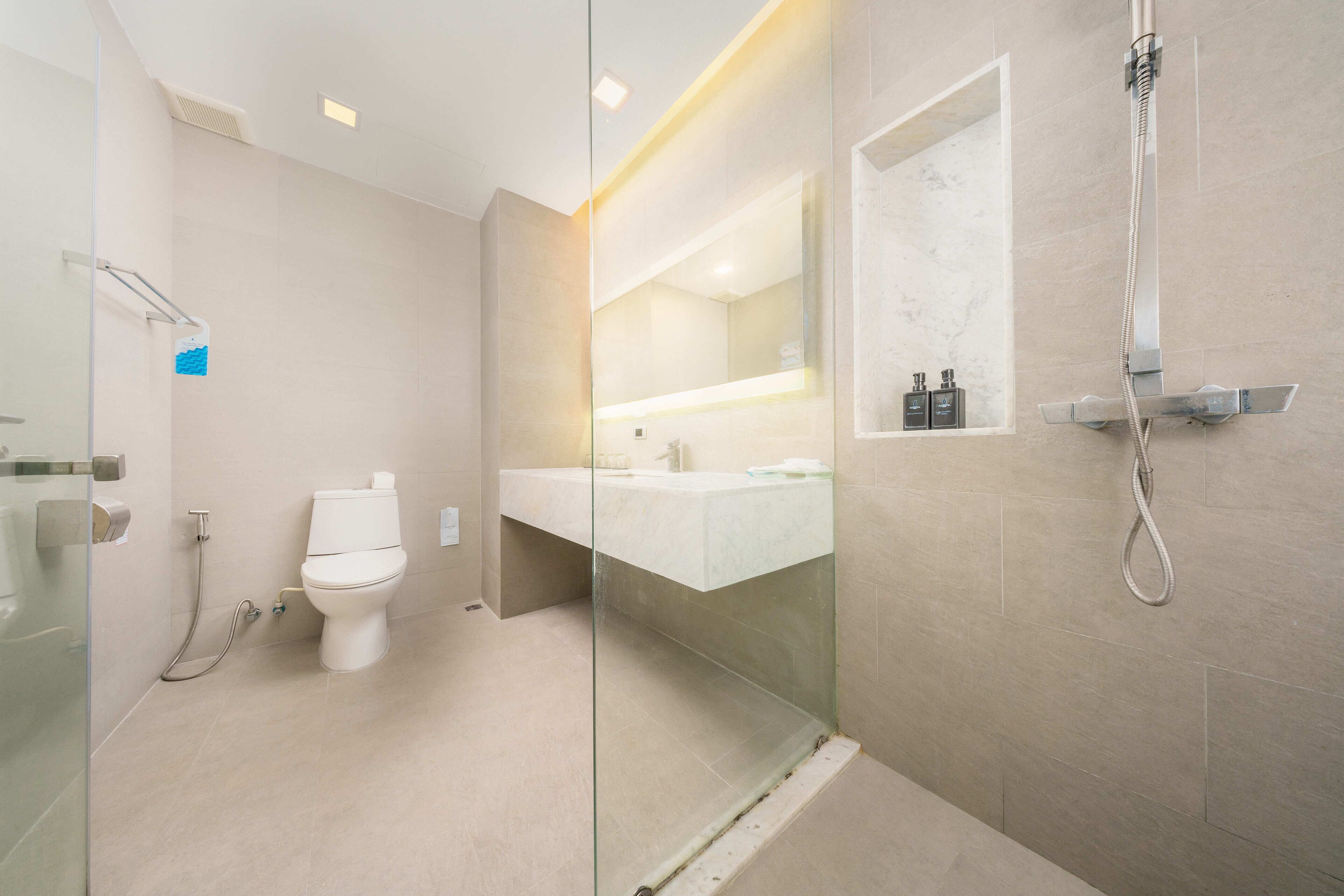 Une salle de bain moderne avec une douche à parois de verre, des toilettes et un meuble-lavabo avec un miroir.