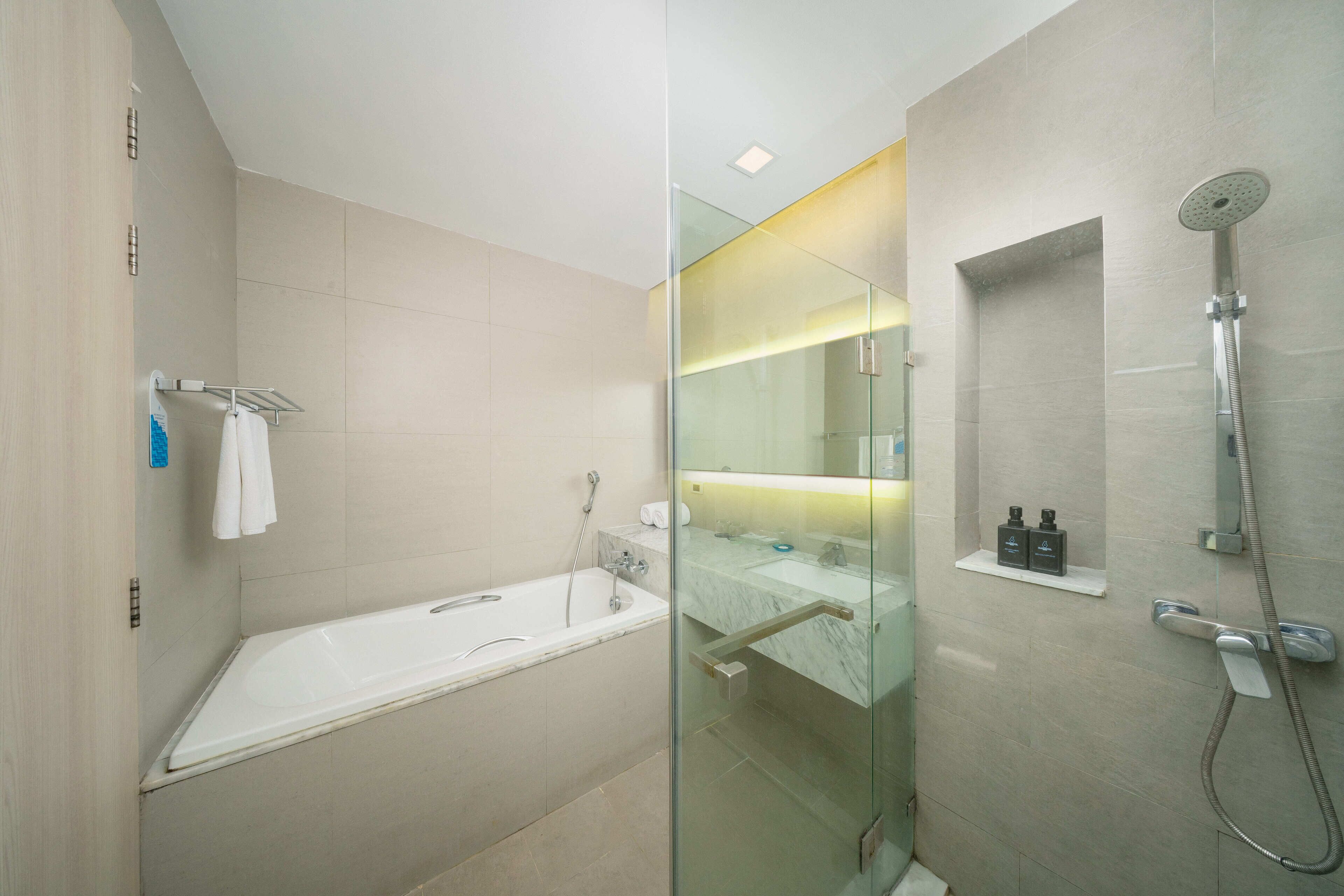 A modern bathroom with a glass-enclosed shower, a standalone bathtub, and a marble-topped vanity.