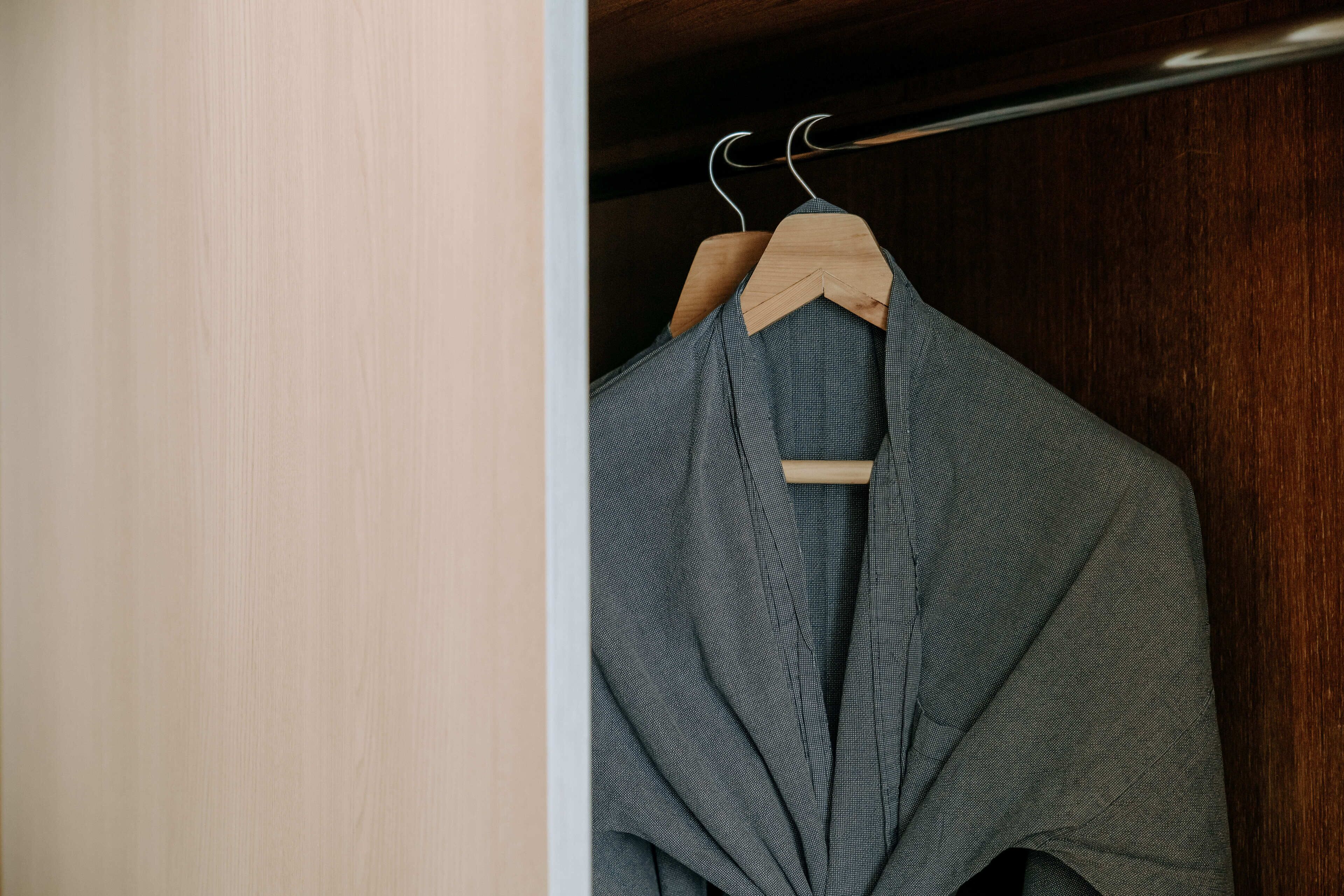 A wooden hanger with a grey garment in a closet.