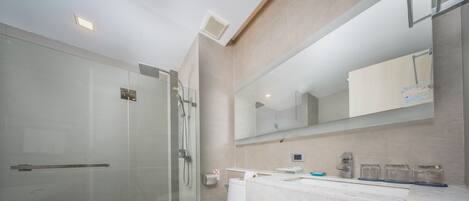 Un bagno moderno con cabina doccia in vetro, un water bianco e un piano d'appoggio in marmo con uno specchio sopra.