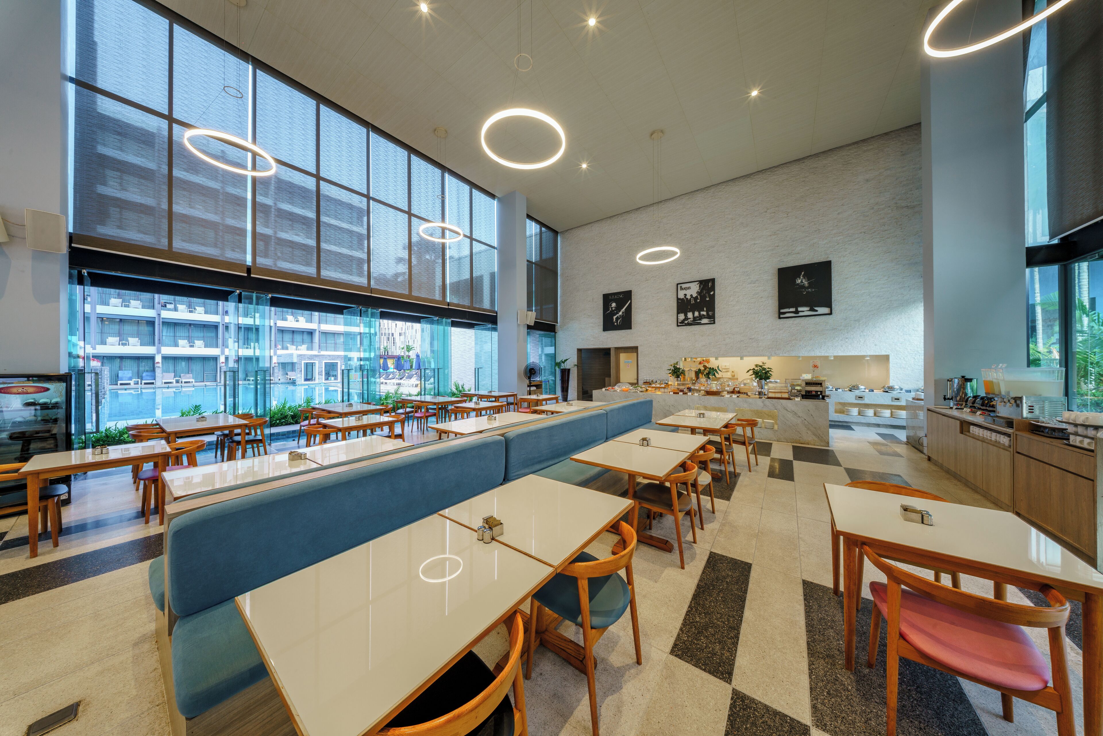 Un restaurante moderno con techos altos, ventanas amplias y una variedad de opciones de asiento, incluyendo mesas y cabinas.