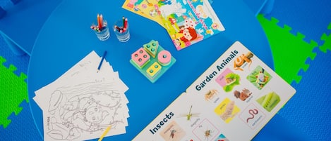 Una mesa con material educativo, incluyendo un dibujo, hojas para colorear y un gráfico de animales e insectos de jardín.