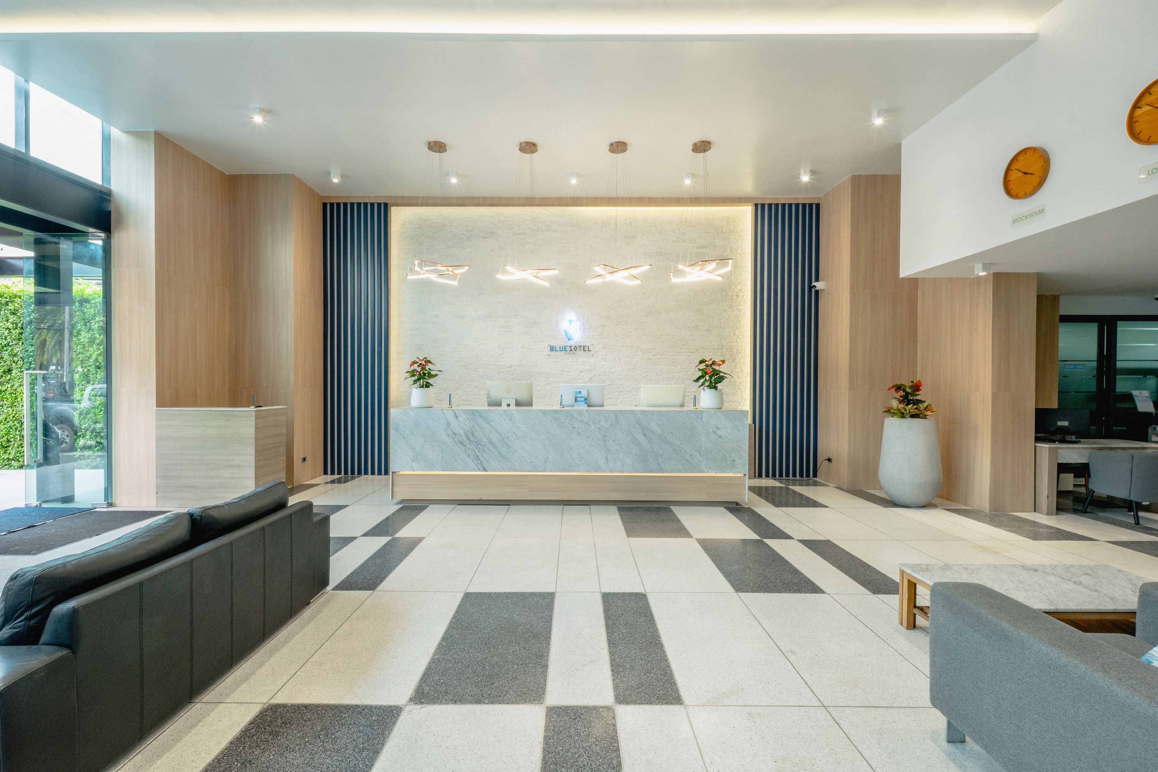 A hotel reception area with a marble counter, seating, and a view of the outdoors.