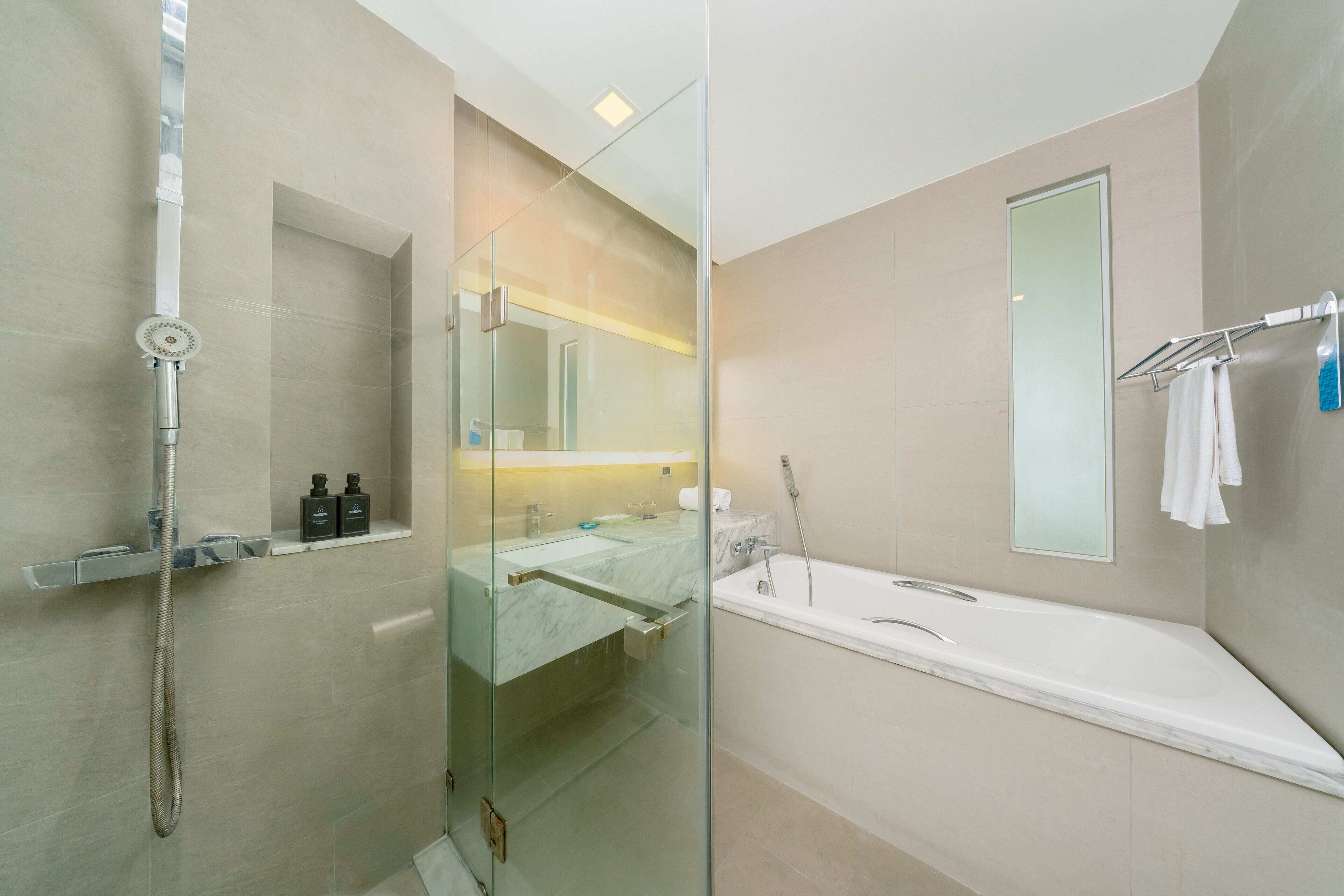 Ein modernes Badezimmer mit einer Glaskabine für die Dusche, einer großzügigen Badewanne und einem Waschtisch mit Spiegel.