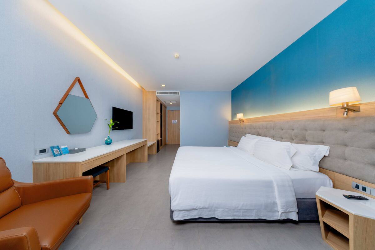 Une chambre d’hôtel moderne équipée d’un grand lit, d’un bureau, d’une chaise et d’un téléviseur.