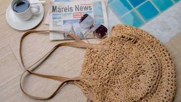 Een zwembadterras met een krant, een kop koffie en een geweven tas.