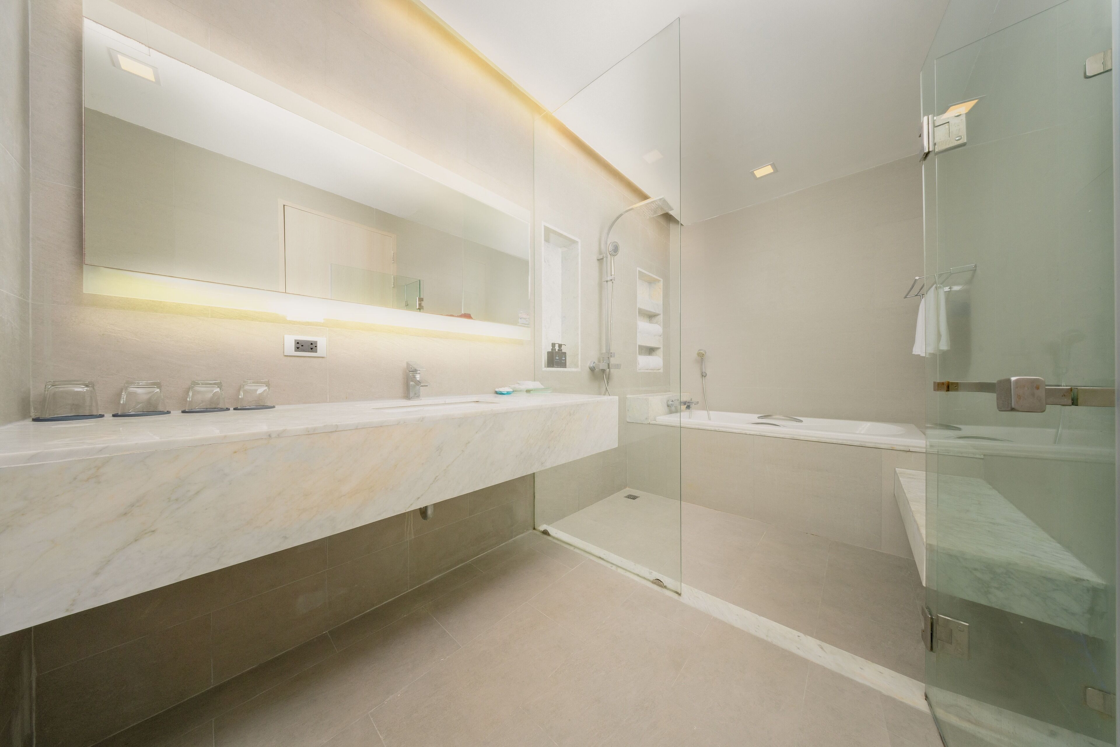 A modern bathroom with a large mirror, two sinks, a shower, and a glass-enclosed walk-in shower.