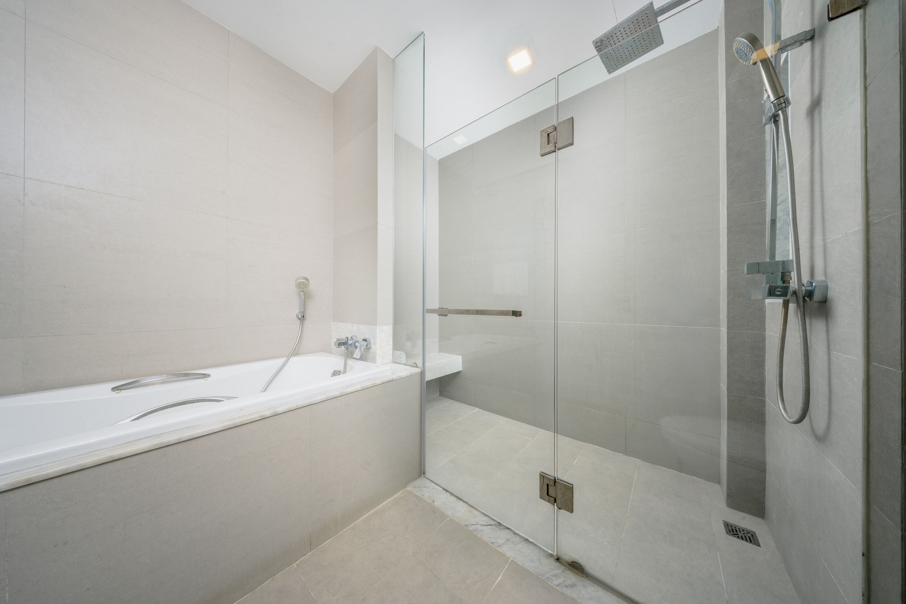 A modern bathroom with a glass-enclosed shower, a white bathtub, and a glass shower door.