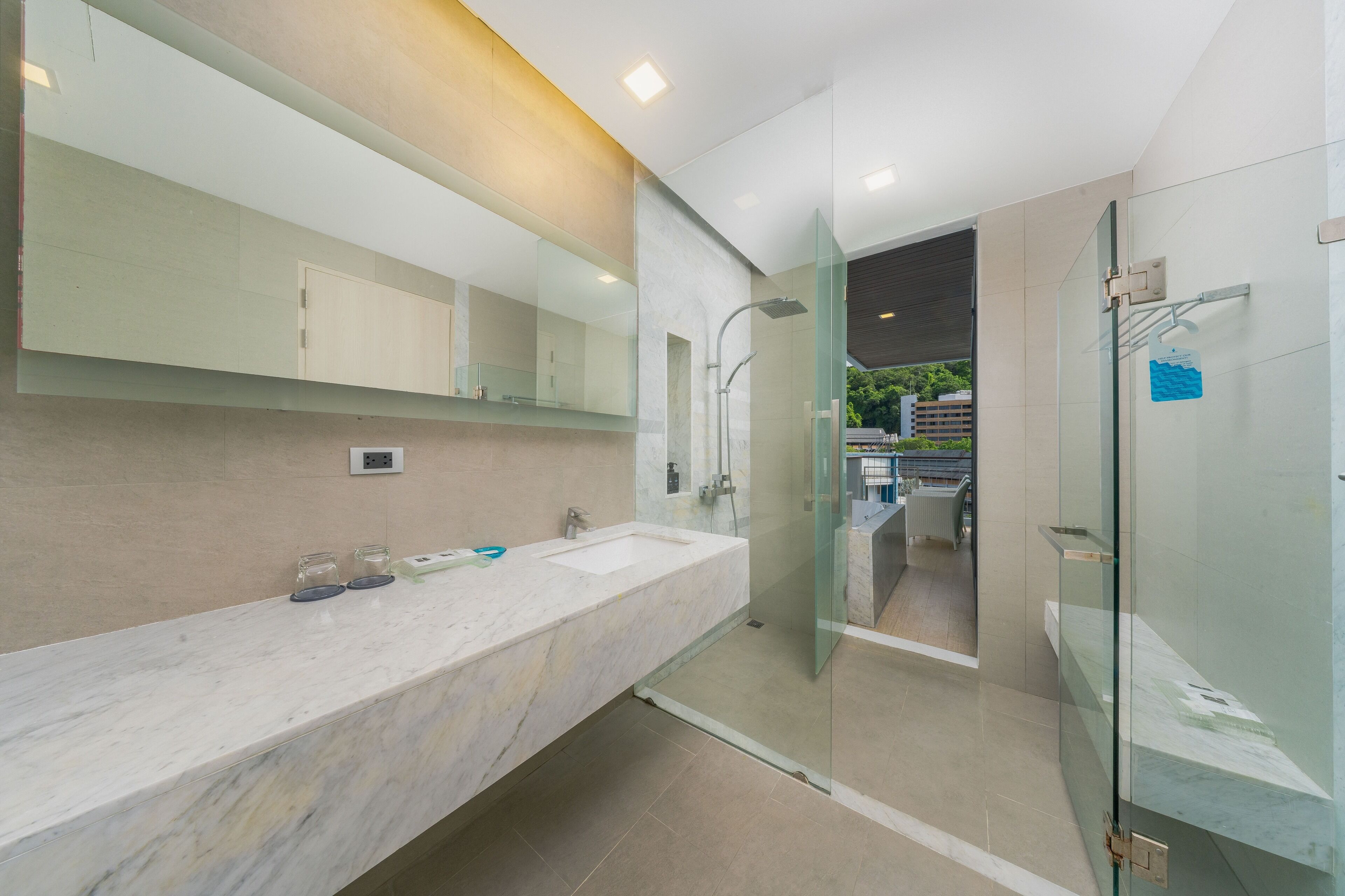 A modern bathroom with a large mirror, two sinks, and a glass-enclosed shower.