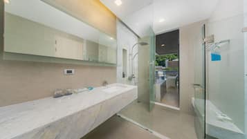 A modern bathroom with a large mirror, two sinks, and a glass-enclosed shower.