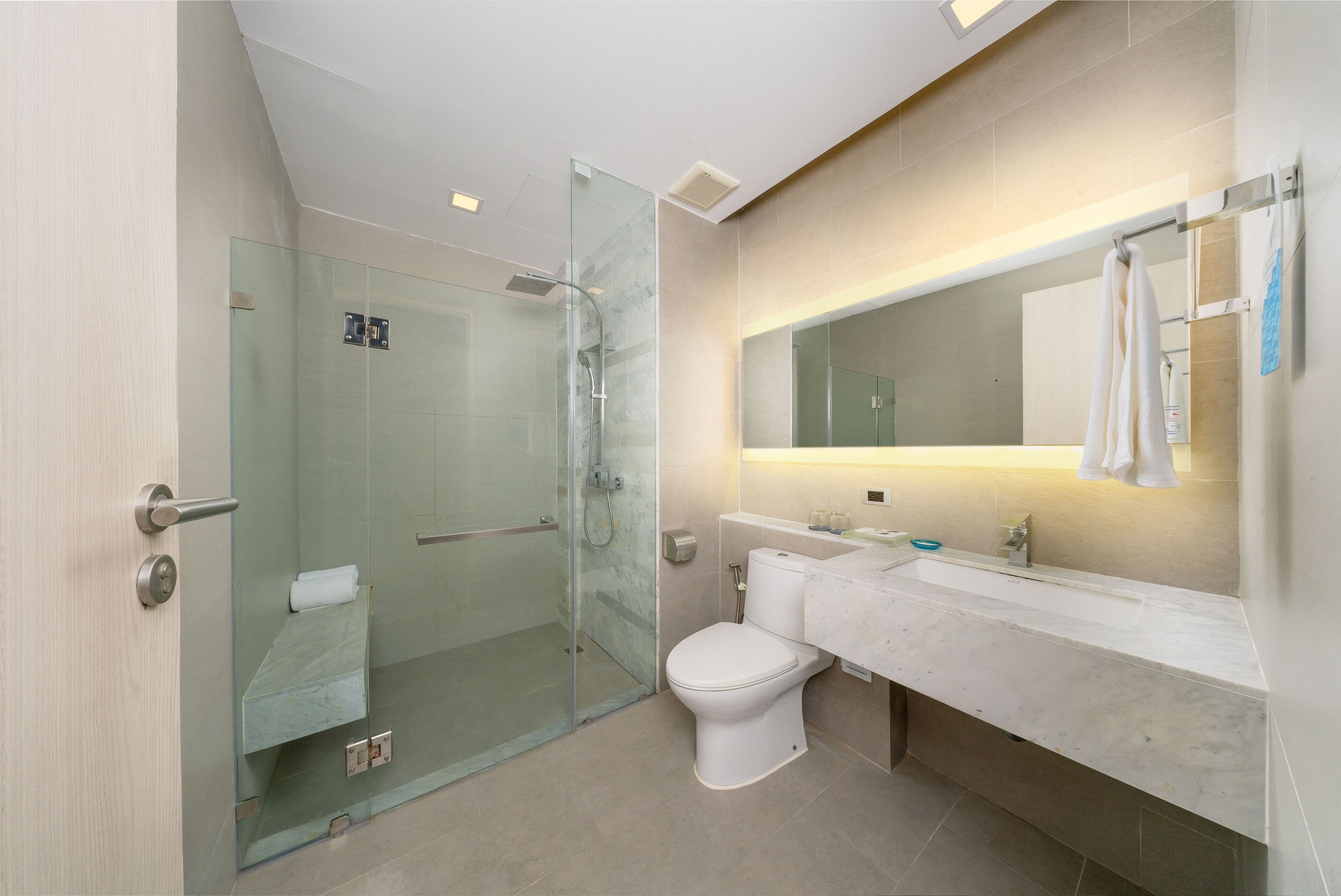 A modern bathroom with a glass-enclosed shower, a white toilet, and a marble vanity with a mirror.