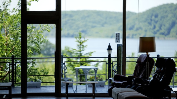 Una habitación con vistas a un lago, una mesa, sillas y un sofá.