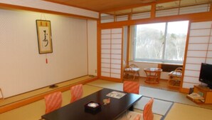 Una habitación tradicional japonesa con suelo de esteras de tatami, una mesa baja y un televisor.