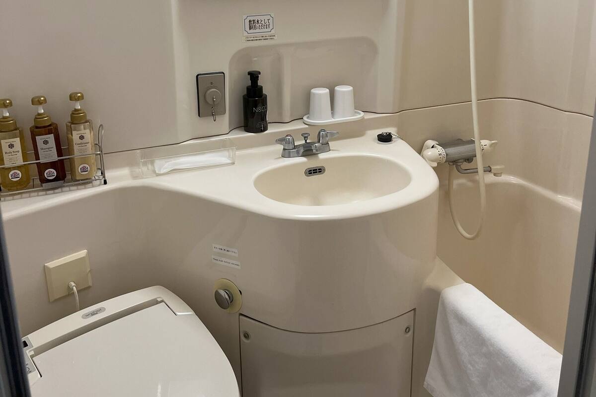 A bathroom with a sink, mirror, toilet, and shower.