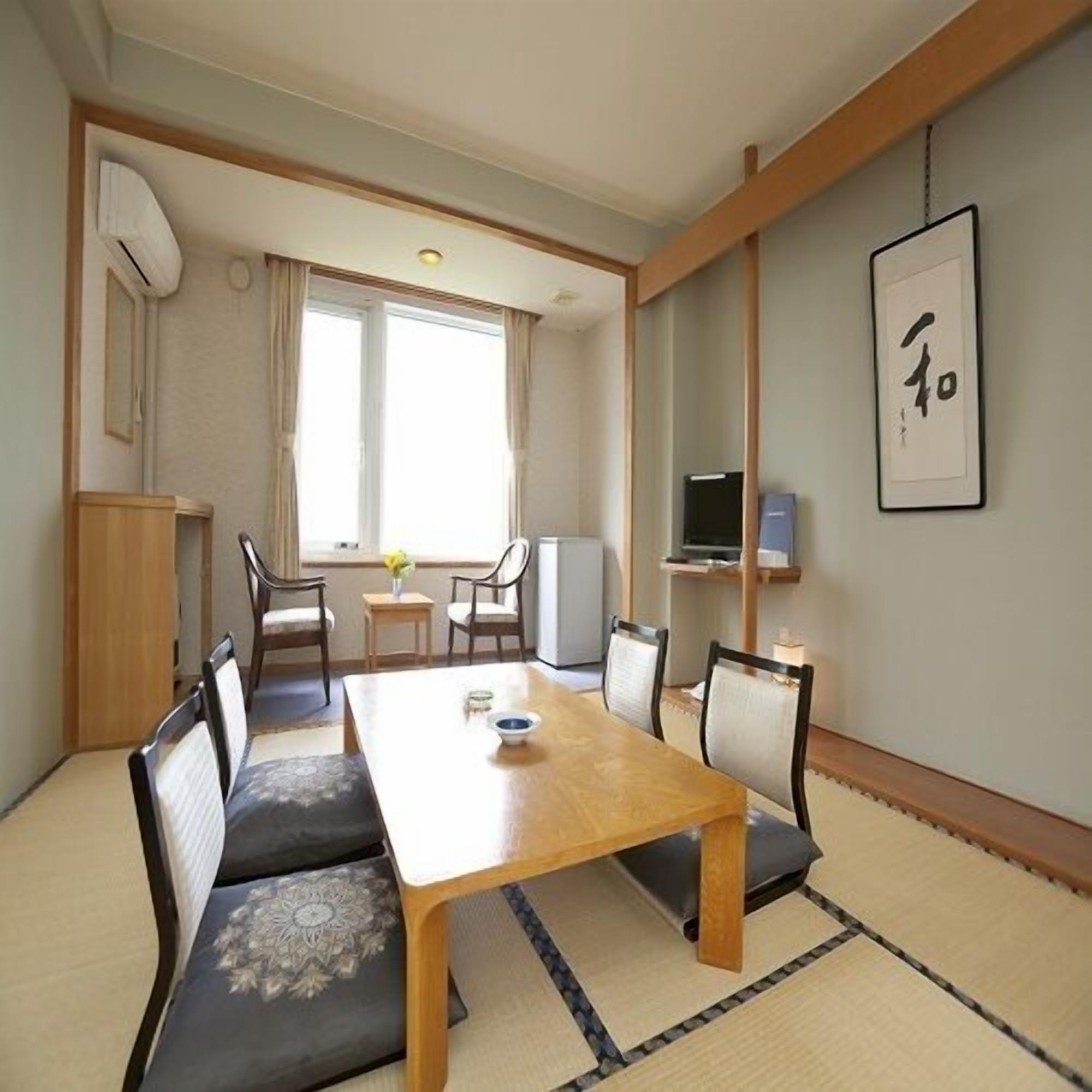 A traditional Japanese-style room with tatami flooring, a low table, and a TV on a shelf.